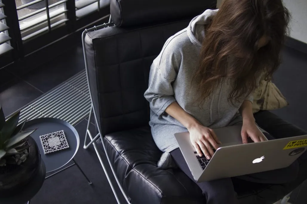 Remote work - woman sitting on black leather chair while using Apple laptop