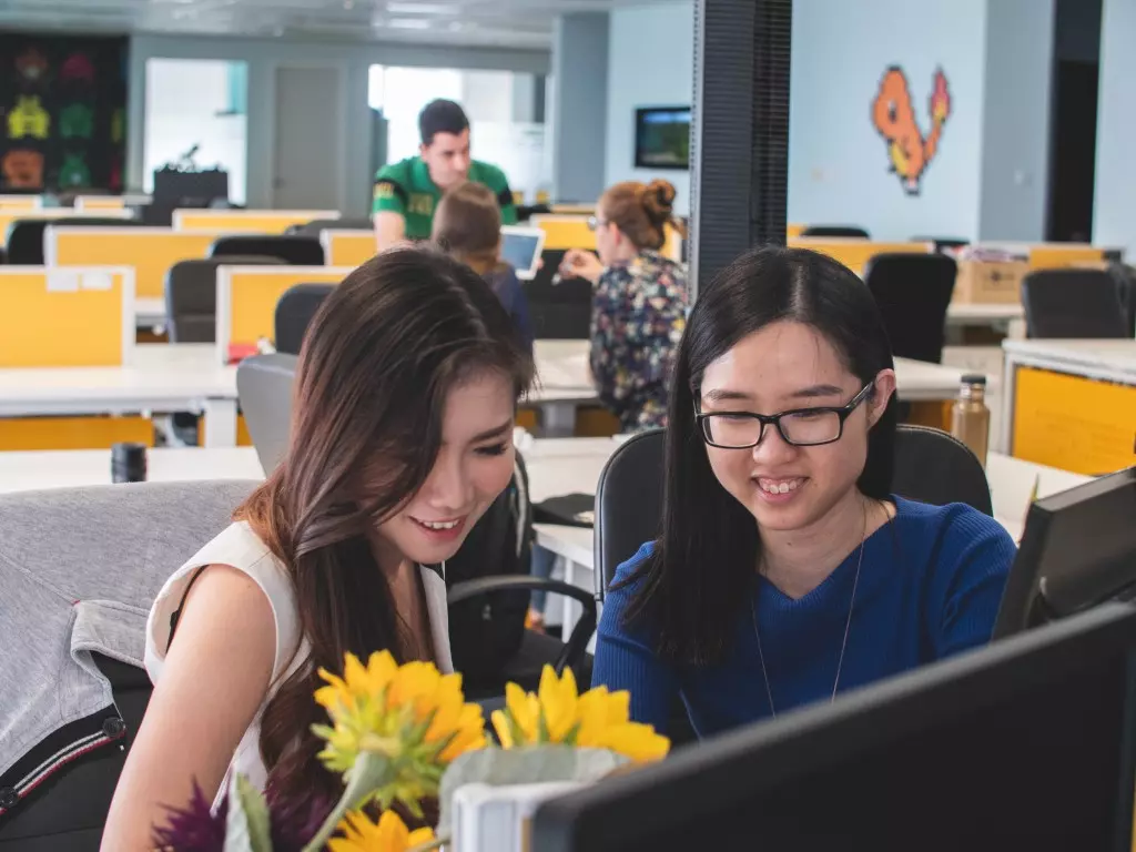 Employee recognition - two women collaborating and working on a desktop computer