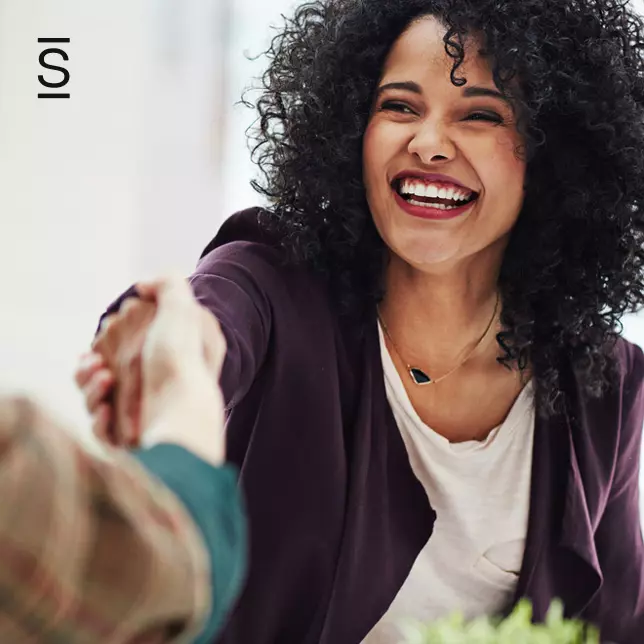 Employee engagement - smiling woman shaking hands with another employee