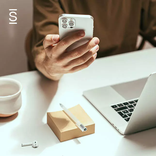 Intranet best practices - man holding smartphone while sitting in front of laptop