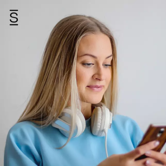 Social company intranet - woman with headphones around neck looking at smartphone