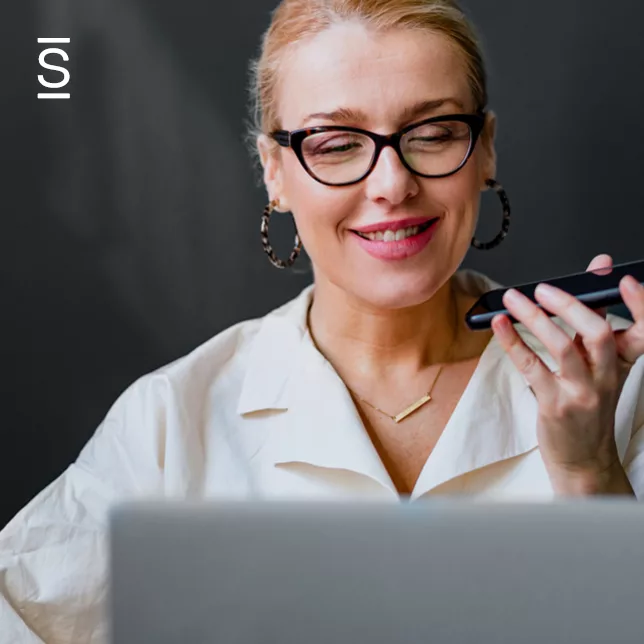 Transparent leadership - woman with glasses speaking into smartphone while using laptop