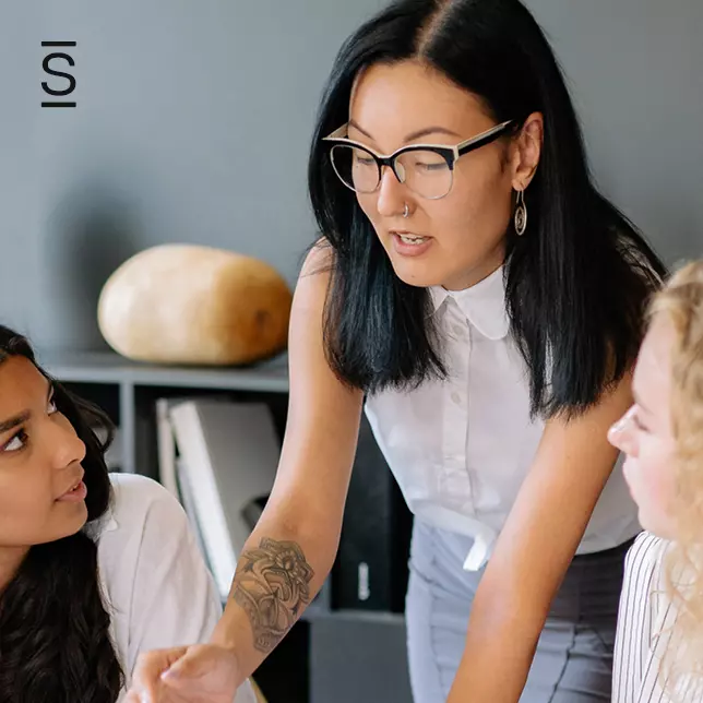 Intranet governance - woman with glasses in sleeveless shirt collaborating with two of her colleagues