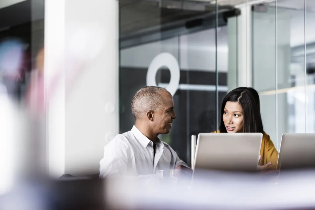 Employee experience - coworkers having a discussion in front of a laptop computer